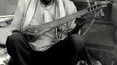 असम का एक गायक गोद में टोकारी रखकर उँगलियों से बजाते हुए गा रहा है